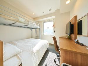 a bedroom with a bed and a desk with a television at Super Hotel Mihara Ekimae in Mihara