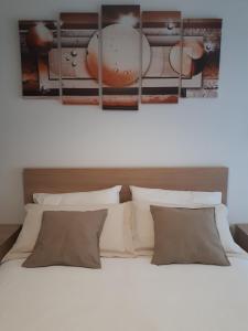 um quarto com uma cama branca com quatro fotografias na parede em SoleLuna Fiera 6 Rooms em Bolonha