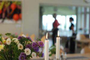 een tafel met twee kaarsen en bloemen erop bij Vadstena Folkhögskola Vandrarhem in Vadstena