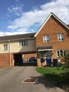 a brick house with a blue door on a street at Cosy Corner House in Kettering