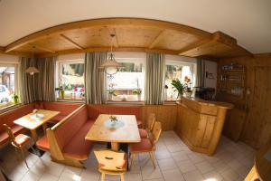 a restaurant with two tables and chairs and windows at Haus Enzian in Sankt Leonhard im Pitztal