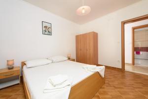 a bedroom with a white bed and a wooden cabinet at Apartmani Petra in Trogir