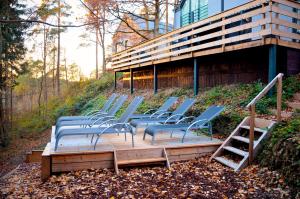 een groep stoelen op een houten terras voor een gebouw bij Villa Dakota - jacuzzi, zwembad, playstation in Durbuy