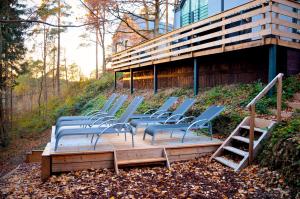 a group of chairs sitting on a wooden deck in front of a building at Villa Dakota - jacuzzi, zwembad, playstation in Durbuy