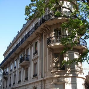 un gran edificio blanco con balcones y un árbol en Pension Bienvenue (Women only) en Lausanne