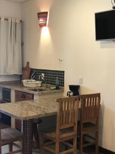 a kitchen with a counter with two chairs and a sink at Suites Grande Tenorio in Ubatuba
