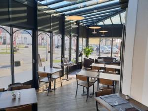 um restaurante com mesas, cadeiras e janelas em Hôtel de la Gare - Restaurant Bistro Quai em La Roche-sur-Yon