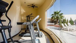 un gimnasio con cinta de correr y vistas a la piscina en American Inn Hotel & Suites Delicias, en Delicias