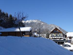 a snow covered house in front of a mountain at B&B Landhof Schober in Weissbriach