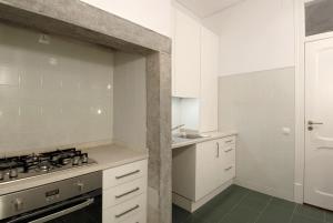 Saldanha Apartment في لشبونة: مطبخ ابيض مع موقد ومغسلة