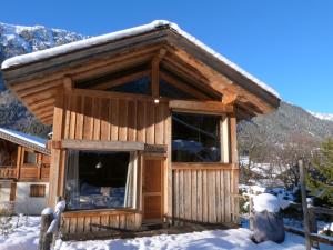 a log cabin with a large window in the snow at La Cubelette in Chamonix-Mont-Blanc