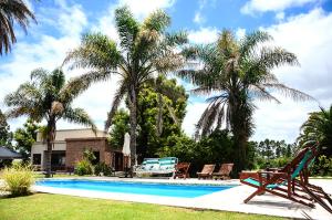 a swimming pool with chairs and palm trees in a yard at La Isolina Club de Campo in Villa María