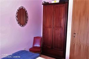 ein Schlafzimmer mit einem Holzschrank und einem roten Stuhl in der Unterkunft Le meridiane in Piè la Costa
