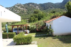 a house with a car parked in a yard with mountains at Salakos Mountain View Home in Sálakos +18 photos