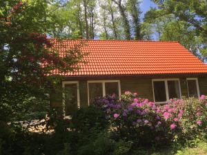 a small house with an orange roof and some flowers at Ferienhof Ohlenbusch in Worpswede