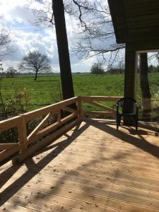 a wooden porch with a bench and a field at Ferienhof Ohlenbusch in Worpswede