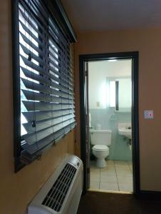 baño con aseo, ventana y lavamanos en Colonial Inn Mercer-Grove City en Mercer