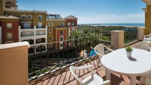 a balcony with a white table and chairs and a building at Leo Isla Canela Selection in Isla Canela