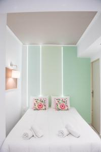 a bedroom with a white bed with pink pillows at Tulip #Colony city center in Thessaloniki