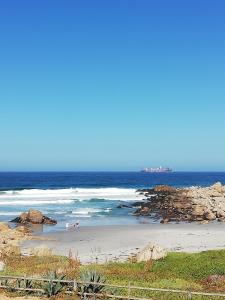 a beach with people walking on the sand and the ocean at Habitaciones Mar Azul in El Quisco
