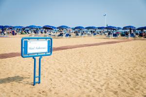 un cartello sulla sabbia di una spiaggia di Mediterranee Family & Spa Hotel a Bibione