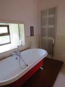 bañera blanca grande en el baño con ventana en The Old House, en Carrick-on-Suir