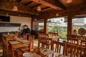 a woman standing in a restaurant with tables and chairs at The Culture Resort in Pokhara