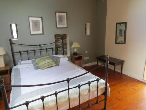 a bedroom with a large bed with white sheets and a table at The Old House in Carrick-on-Suir