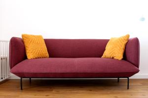 Un sofá púrpura con dos almohadas amarillas. en Miradouro's Loft, en Setúbal