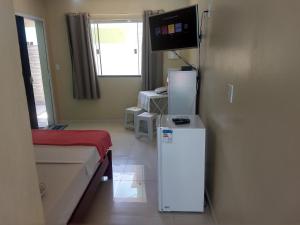 a room with a refrigerator and a tv on the wall at Seasun Suítes in Arraial do Cabo