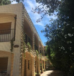 un edificio con un árbol al lado en Apart Hotel Sahara en Pinamar