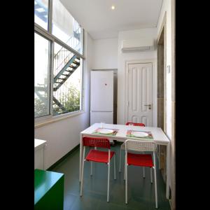 Saldanha Apartment في لشبونة: مطبخ مع طاولة بيضاء وكراسي حمراء