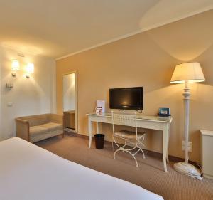 Habitación de hotel con cama y escritorio con TV. en Hotel Canon d'Oro en Conegliano