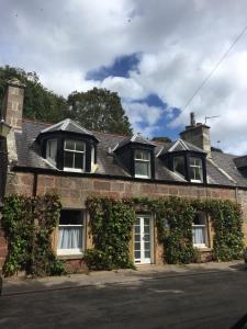 a brick house with ivy on the side of it at 3 St Gilbert Street in Dornoch
