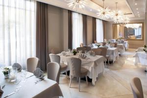 a restaurant with white tables and chairs and windows at Hotel Dei Fiori Restaurant - Meeting & Spa in Alassio