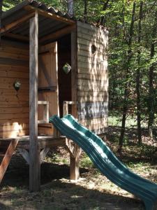 un tobogán verde frente a una cabaña de madera en Chalets du Bois de Vache, en Le Poët-Célard