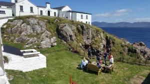 un grupo de personas sentadas en una colina con una casa en Fanad Lighthouse, en Letterkenny