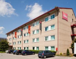 a large building with cars parked in a parking lot at Ibis Cornella in Cornellà de Llobregat