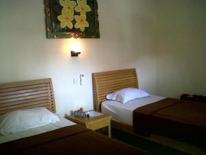 Kirana Home Stay في سانور: غرفة فندقية بسريرين وصورة على الحائط