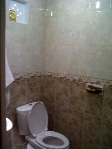 a bathroom with a toilet and a tiled wall at Kirana Home Stay in Sanur