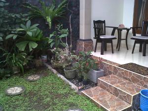 un patio con un montón de plantas y sillas en Kirana Home Stay, en Sanur