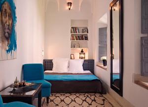 a small bedroom with a bed and a blue chair at Riad Dar Hanane in Marrakesh