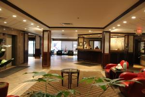 un vestíbulo de un hotel con sillas rojas y una mesa en Nomad Hotel & Suites, en Fort McMurray