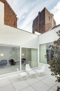 a patio with white chairs and a building at Zenden Hotel Maastricht in Maastricht
