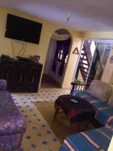 a living room with a couch and a flat screen tv at tamazirt surf house in Taghazout