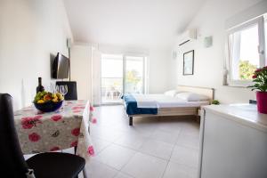 a white room with a bed and a table with a table sidx sidx at Apartment Milka 1 in Njivice