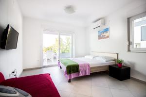 a white bedroom with a bed and a window at Apartment Milka 1 in Njivice