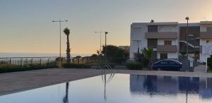 a swimming pool with a palm tree and a building at Appartement avec piscine à Imi ouaddar plage in Imi Ouaddar