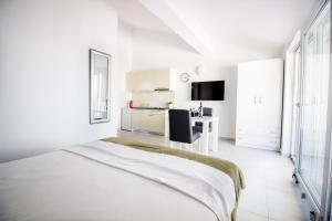 a white bedroom with a bed and a desk at Colic in Njivice