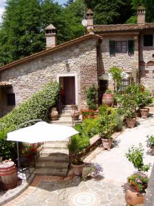 - un bâtiment en pierre avec un parasol devant dans l'établissement Camera Rosa, à Borgo a Buggiano